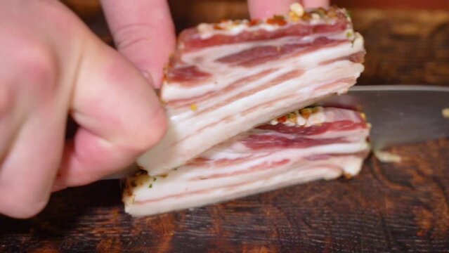 Slicing of salted pork fatback on cutting board, close-up. Ukrainian traditional food - salo	
