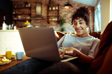 Relaxed woman enjoying her time browsing on a laptop in a warm-lit room