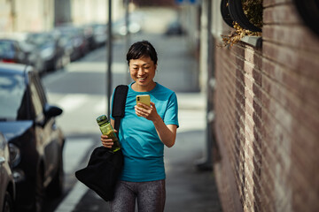Rejuvenated woman checks her phone after a gym session