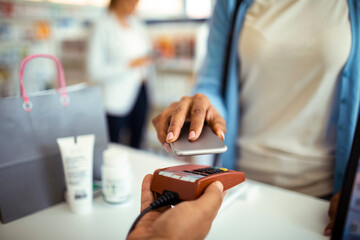 Close up of customer makes a digital payment at a pharmacy counter