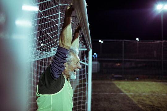 Fototapeta Elderly goalkeeper guarding the goal on a soccer pitch at night