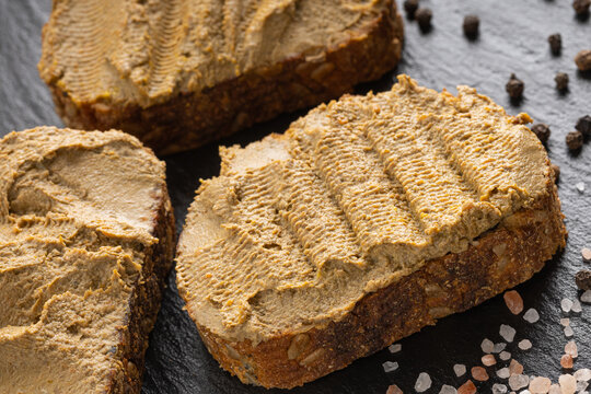 liver pate  spread on the bread fuagra chicken pate closeup space for text sand wich in the hand salt and pepper behaind