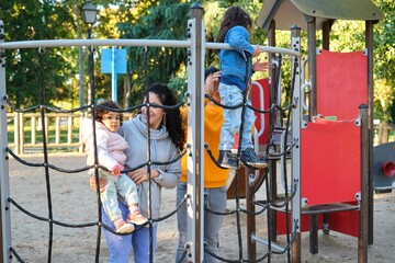 Hispanic family with two children playing climbing in a playground. Latin family.