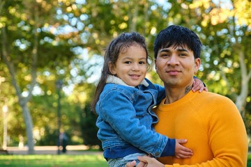 Portrait of happy Ecuadorian father holding his son in a park.
