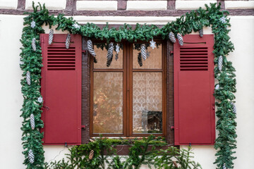 window with red blinders decorated with pine fir and cones for new year