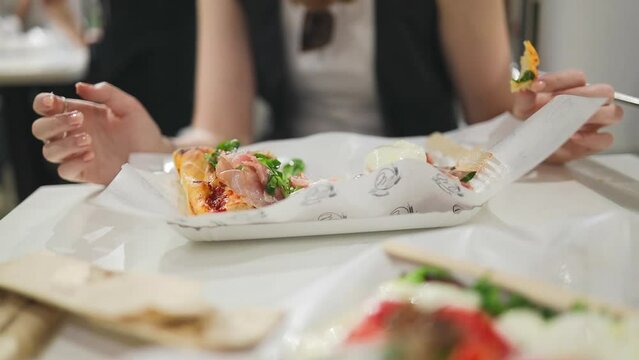 Italian focaccia with with burrata cheese and ham in the hands. female hands holding Focaccia barese slice at street cafe. High quality FullHD footage