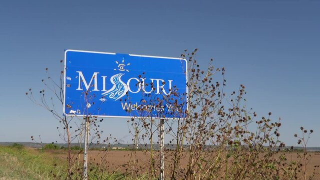 Missouri Welcomes You - a roadside sign at a state border with Nebraska, fall scenery with dry sunflowers moved by wind