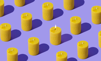 Creative pattern composition of beeswax candles made with natural wax produced by honey bees on pastel violet background. Minimal pattern background hope concept. Trendy beeswax candle idea.