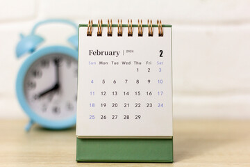 Desk calendar for February 2024 and a clock on the table.