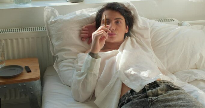 Concerned young man smoking in bed, guy looks depressed as he has broken with girlfriend Slow motion