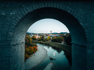 Aerial view of a small city nestled in a mountain valley as seen through an old bridge over the...