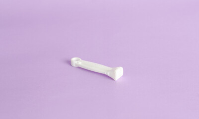 Clamp, umbilical cord cutter isolated on violet background, close up. Operating room elements in childbirth.