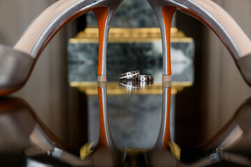 Elegant high heels frame gleaming wedding rings, mirrored below, showcasing a moment of love and...