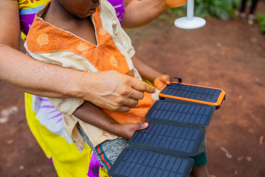 Close-up of a solar panel held by an African child while his mother explains how it works