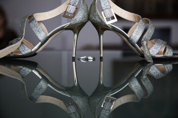 Shimmering bridal heels with a crystalline texture on a reflective surface, symmetrically framing a...