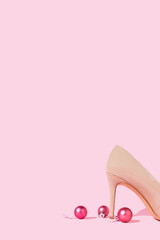 High heell shoe and Christmas ornament decorations on pastel pink background. Holiday celebration party concept. Copy space.