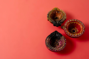 Happy Diwali and Kartika Deepam Festival Greetings - Colorful clay diya lamps on red background