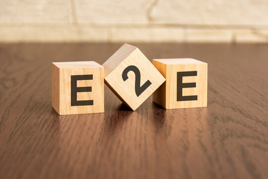 Exchange to Exchange concept with symbols E2E on wooden cubes, dark wooden background