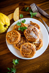 Cooked fried round pancakes with quince filling on a wooden table