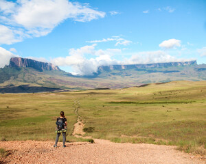 Obraz premium woman with backpack, in trekking to Roraima Mountain, in Venezuela, with mountains in background 