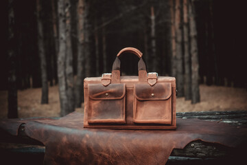 Vintage leather travel bag on the wooden table in the forest
