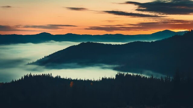 Sunrise sea of fog moving over mountain range. Time lapse alps mountain silhouette with pine tree forest aerial view. Wild nature mist landscape. Dramatic dark clouds float in orange colored sky