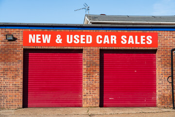 Used Car Sale company with Closed Garage doors with text above 