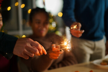 Group of diverse ethnicity young people enjoy celebrating a Christmas and New Year party together with a lot of foods and drinks and enjoy playing with sparkling bengal light - fireworks together.