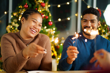Group of diverse ethnicity young people enjoy celebrating a Christmas and New Year party together with a lot of foods and drinks and enjoy playing with sparkling bengal light - fireworks together.