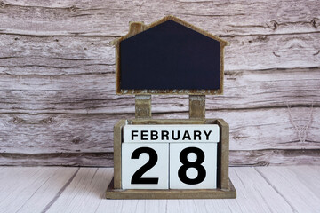 Chalkboard with date on white cube block on wooden table.