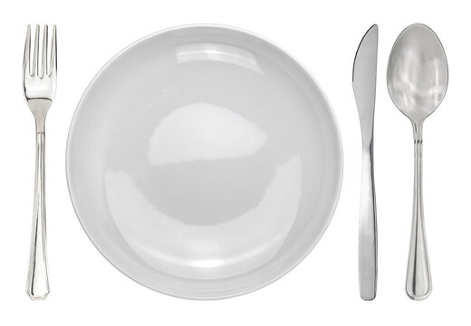 Table setting with a white plate next to cutleries. Plate with fork and knife and spoon isolated