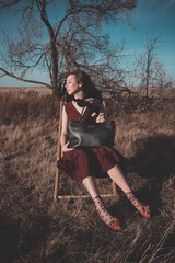 woman sitting on a chair outdoors with leather bag