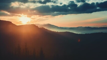 Epic foggy colorful sunrise in alp mountains. Dramatic clouds flow in bright sky, sun glow rising over mountain peak with golden light beams. Beautiful morning nature summer landscape. Time lapse