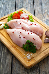 Fresh raw chicken breasts on cutting board with spices on wooden background
