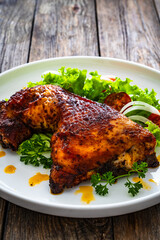 Roasted chicken thigh with lettuce and tomato on wooden table
