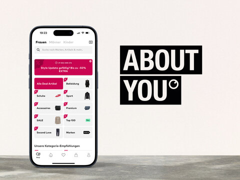 Modernes Smartphone zeigt App des Online-Versandh&auml;ndlers ABOUTYOU, Logo des Online-Versandh&auml;ndlers daneben, Mode, Fashion, Bekleidung, Schuhe, Kosmetik, E-Commerce, Internet, Versand