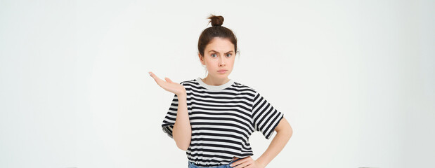Portrait of confused girl, shrugging should and raising one hand up, looks puzzled, cant understand something, standing over white background - obrazy, fototapety, plakaty