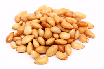 Roasted pine nuts, presented on a white surface, are isolated.