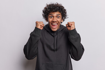 Emotional Hindu man with curly hair rejoices victory or success reacts emotionally to something...