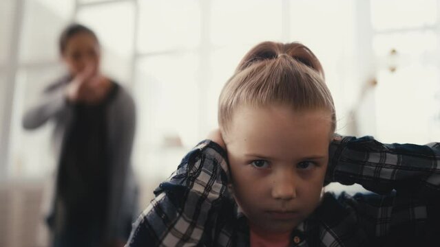 Child closing ears with palms while angry mom scolding, verbally abusive parent