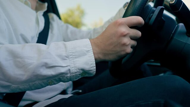 close-up of hands of a male driver behind the wheel in the interior of a luxury car driving in the city