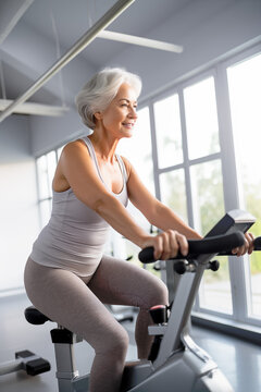 Elderly woman exercising on an exercise bike, joyful senior woman, Healthy Active Lifestyle. Generated by AI.