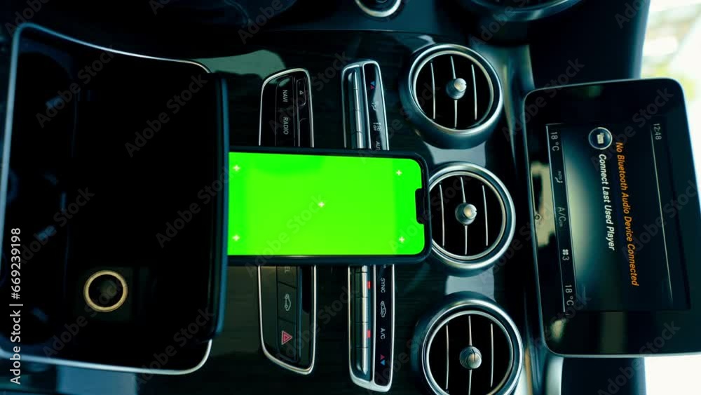 Wall mural vertical video close-up of a phone with a green screen display stands on the dashboard in a luxuriou