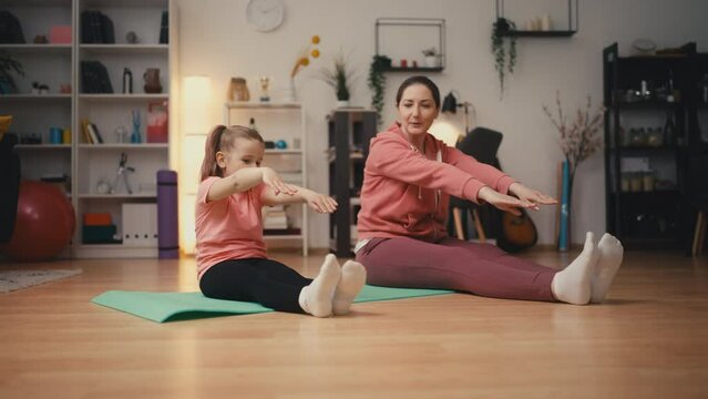 Mother teaching daughter healthy lifestyle, doing stretching exercises together