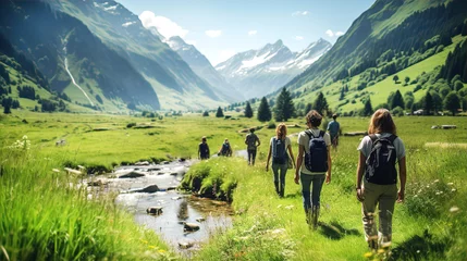 Fotobehang Sunny day in Alps, candid photo group of people hiking together in mountains, walking by river stream,  beautiful green fields and snow covered mountains © IRStone