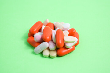 White spoon with colorful medical pills on green background, copy space 