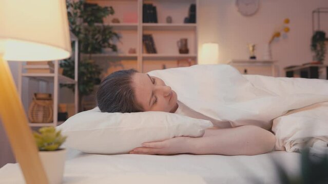 Woman in her 30s waking up in the morning and stretching hands, healthy sleep
