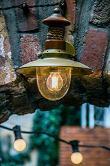 A light bulb burns in a lantern close-up against the background of a brick arch and lanterns