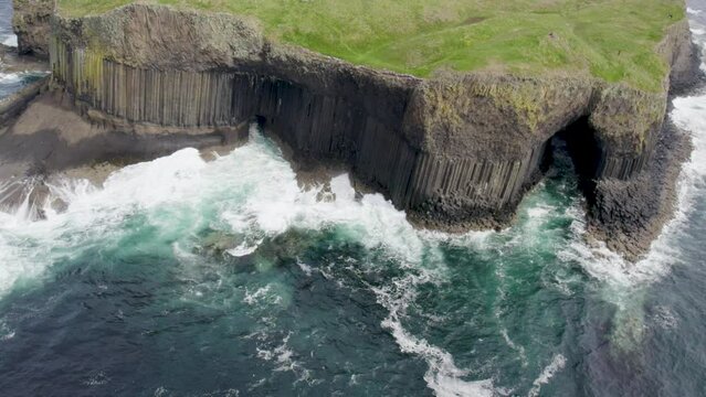 Aerial view flying over a Fingal's Cave on Staffa Island, west of Isle of Mull in Scotland. Calm waves touching the rocks.