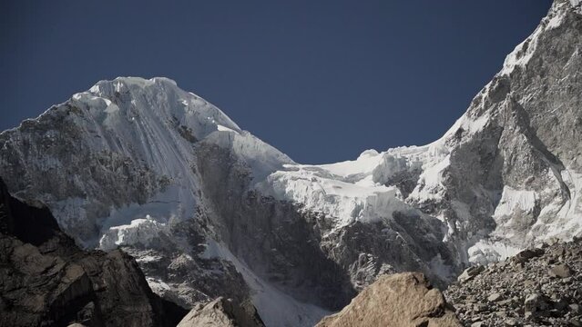 ice covered glacier of a pyramid shaped mountain at laguna paron lagoon in the high andes mountains of the cordillera blanca at huascaran, Peru, with snow covered mountain peaks on a bright sunny day.